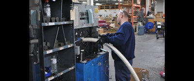 A JGB employee feeds a large hose through a crimping machine. (JGB photo)