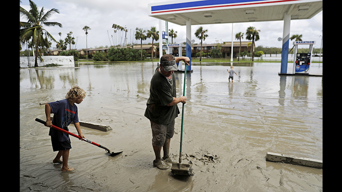 Chris Stokes, right, cleans up mud brought in with the storm surge from Hurricane Irma with help from his son Chase, 9, at his father's convenience store in Everglades City, FL., on Monday, Sept. 11. (AP Photo/David Goldman)