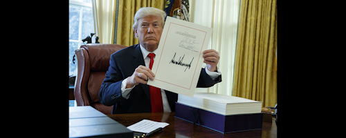 President Donald Trump shows off the tax bill after signing it in the Oval Office of the White House, Friday, Dec. 22, in Washington. (AP Photo/Evan Vucci)