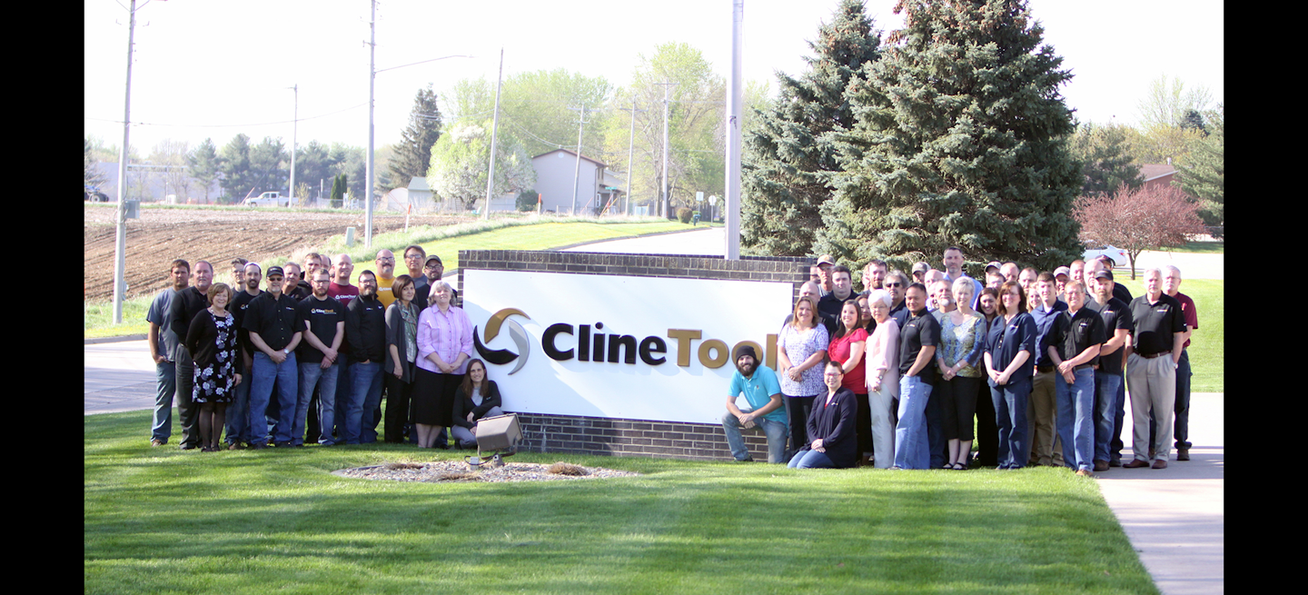 Employees at Cline Tool's Newton, IA headquarters pose around the company's front lawn sign.