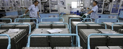 In this July 27, 2018, photo, workers transfer Lithium-ion batteries in a factory in Taizhou in east China's Jiangsu province. Chinatopix via AP)