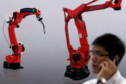A visitor talks on his smartphone in front of a display of manufacturing robots from Chinese robot maker Honyen at the World Robot Conference on Aug. 15 in Beijing, China.