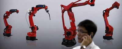 A visitor talks on his smartphone in front of a display of manufacturing robots from Chinese robot maker Honyen at the World Robot Conference on Aug. 15 in Beijing, China.