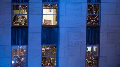 In this Nov. 28, 2018 file photo, people work in their office after the Rockefeller Center Christmas tree is lit during the 86th annual Rockefeller Center Christmas tree lighting ceremony in New York.