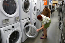 In this Monday, Sept. 23, 2019 photo Maria Alvarez, front, and her husband Guillermo Alvarez, behind, both of Boston, examine clothes washers and dryers at a Home Depot store location, in Boston.