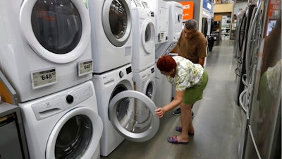In this Monday, Sept. 23, 2019 photo Maria Alvarez, front, and her husband Guillermo Alvarez, behind, both of Boston, examine clothes washers and dryers at a Home Depot store location, in Boston.