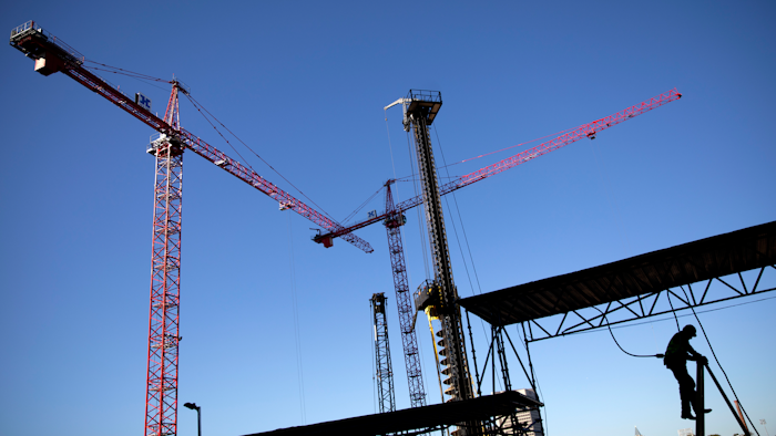 In this Oct. 23 file photo, a worker climbs a ladder as cranes work the construction site for the new corporate headquarters of Norfolk Southern Railway in Atlanta.