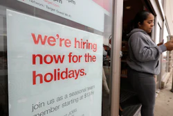 In this Nov. 27, 2019 photo, a passer-by walks past a hiring for the holidays sign near an entrance to a Target store location, in Westwood, MA.