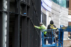 In this Nov. 27, 2019 photo, workers use a lift while working on a new building in Boston's Seaport district.