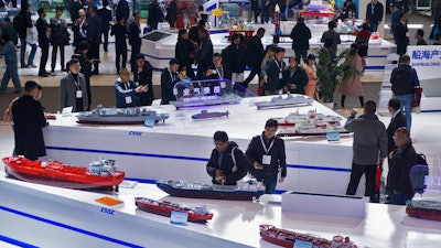 In this Dec. 3, 2019 photo, visitors look at the ship models exhibited by the China State Shipbuilding Corporation (CSSC) during the Marintec China exhibition in Shanghai, China.