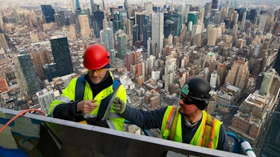 In this March 8, 2019, file photo, work continues on an outdoor observation deck on the 30 Hudson Yards office building in New York. Business economists expect U.S. economic growth to slow this year and next, but they say the economy will avoid recession.