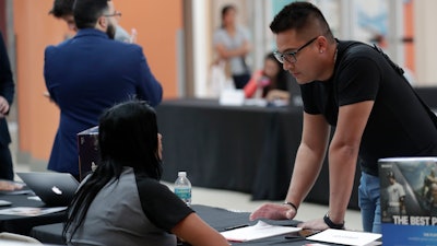 In this Oct. 1, 2019 file photo, Gabriel Picon, right, talks with a representative from GameStop during a job fair at Dolphin Mall in Miami.