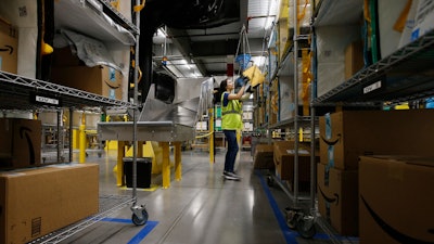 In this Dec. 17, 2019, file photo Jocelyn Nieto stows packages into special containers after Amazon robots deliver separated packages by zip code at an Amazon warehouse facility in Goodyear, AR.