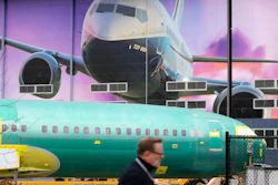 In this Dec. 16, 2019 file photo, a Boeing worker walks past a 737 model fuselage and a giant mural of a jet on the side of the manufacturing building behind in Renton, WA.