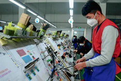 In this Feb. 13 photo, masked workers assembly wiring for automobile at a factory in Qingdao in east China's Shandong province. Automakers are gradually reopening factories in China that were idled by anti-virus controls as they try to reverse a sales slump in their biggest market.