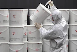 A worker in protective gear stacks plastic buckets containing medical waste from coronavirus patients at a medical center in Daegu, South Korea on Monday, Feb. 24. South Korea reported another large jump in new virus cases Monday a day after the the president called for 'unprecedented, powerful' steps to combat the outbreak that is increasingly confounding attempts to stop the spread.