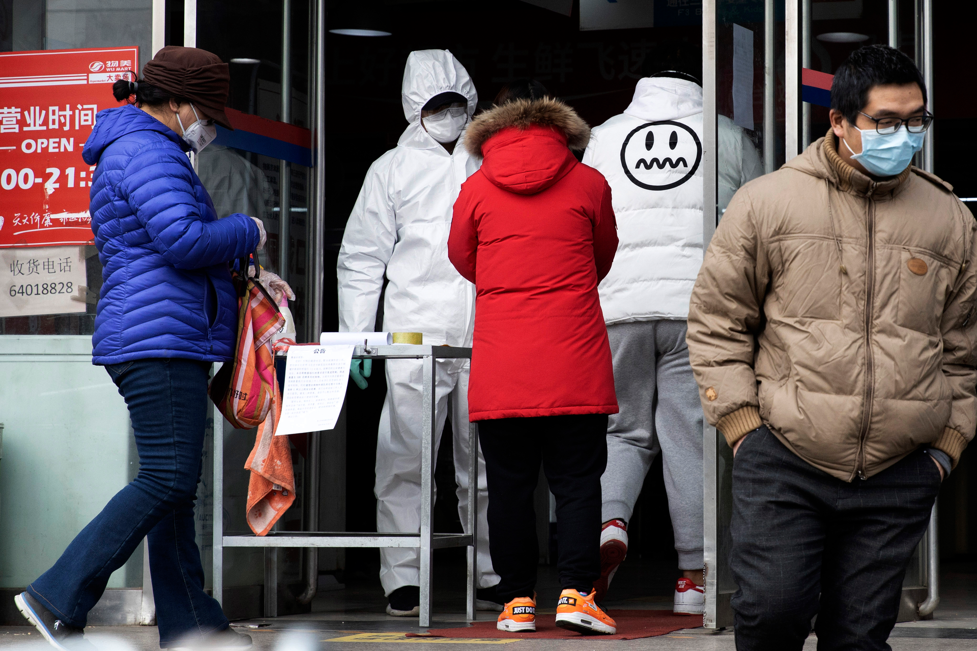 A worker in overalls screen for fever at the entrance to a supermarket in Beijing on Thursday, Feb. 27. South Korea and China each reported hundreds more virus cases Thursday as the new illness persists in the worst-hit areas and spreads beyond borders.
