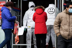 A worker in overalls screen for fever at the entrance to a supermarket in Beijing on Thursday, Feb. 27. South Korea and China each reported hundreds more virus cases Thursday as the new illness persists in the worst-hit areas and spreads beyond borders.
