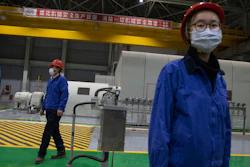 Workers stand in the generator room at the Huadian Beiran Corporation's power plant in Beijing on Thursday, Feb. 27. The state-owned company's steam and gas combined cycle power plant on the outskirts of the nation's capital, which opened in 2017 and provides electricity and heat to the Tongzhou District, managers have instituted virus prevention measures include masks, disinfection wipes, and measuring body temperature for employees entering the premises.