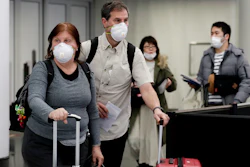 Travelers wear protective masks as they walk through in terminal 5 at O'Hare International Airport in Chicago on Sunday, March 1.
