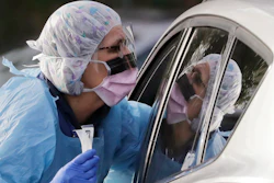 In this March 17 photo, Laurie Kuypers, a registered nurse, reaches into a car to take a nasopharyngeal swab from a patient at a drive-through COVID-19 coronavirus testing station for University of Washington Medicine patients in Seattle.