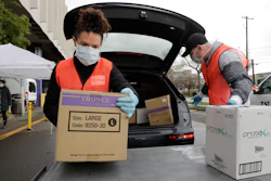 Volunteers Keshia Link, left, and Dan Peterson unload boxes of donated gloves and alcohol wipes from a car at a drive-up donation site for medical supplies at the University of Washington to help fight the coronavirus outbreak on Tuesday, March 24 in Seattle.