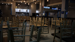 In this March 16, 2020 file photo, chairs hang stacked on empty tables at a closed restaurant in New York.