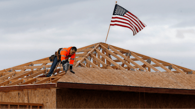 The American flag flutters in the wind as work is done on the roof of a building under construction in Sacramento, CA on Tuesday, March 31. While most Californian's have spent more than a week under a mandatory stay-at-home order, because of the coronavirus, construction work is among the jobs exempt as part of the 'essential infrastructure.'