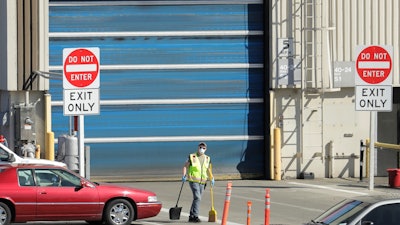 In this April 13 photo, a worker wears a mask as he cleans up an area outside an entrance at Boeing Co.'s airplane assembly facility in Everett, WA, north of Seattle. American industry collapsed in March as the coronavirus pandemic wreaked havoc on the U.S. economy. Manufacturing and overall industrial production posted the biggest drops since the United States demobilized after World War II.