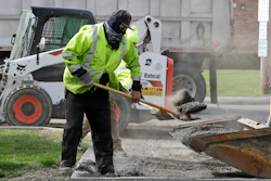 In this May 6 photo, Jarrett Barth, who works for Dagg's Asphalt & Sealcoating, shovels gravel into a backhoe bucket in Lyndhurst, OH.
