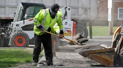 In this May 6 photo, Jarrett Barth, who works for Dagg's Asphalt & Sealcoating, shovels gravel into a backhoe bucket in Lyndhurst, OH.