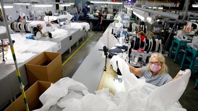 Angie Moorefield unfolds material to begin sewing a disposable gown at Burlington Medical in Newport News Wednesday, May 6. The manufacturing business recently shifted from producing radiation protection gear for medical facilities to in-demand personal protective equipment such as masks, gowns and plastic face shields.