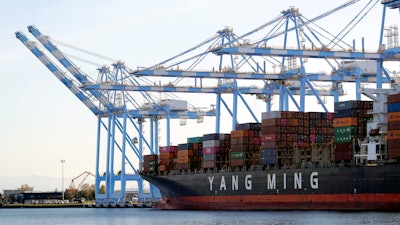 In this Nov. 4, 2019 file photo, cargo cranes are used to take containers off of a Yang Ming Marine Transport Corporation boat at the Port of Tacoma in Tacoma, WA.