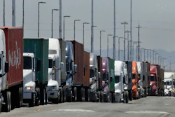 In this July 22, 2019 photo, trucks hauling shipping containers wait to unload at the Port of Oakland in Oakland, CA.