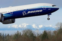 In this Jan. 25, 2020, file photo a Boeing 777X airplane takes off on its first flight with the Olympic Mountains in the background at Paine Field in Everett, Wash. Boeing on Wednesday, May 27, is cutting more than 12,000 jobs through layoffs and buyouts as the coronavirus pandemic seizes the travel industry. And the aircraft maker says more cuts are coming.