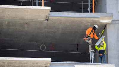 In this May 20 photo, a construction worker stands on stilts while working at a residential building construction site at the Harbor Point redevelopment site on the Stamford, CT waterfront.