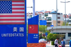People walk by a display boards featuring the U.S. and Chinese flags.