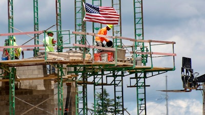 In this June 11, 2020 file photo, workers on scaffolding lay blocks on one of the larger buildings at a development site where various residential units and commercial sites are under construction in Cranberry Township, Butler County, PA