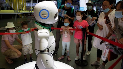 Visitors wearing masks to protect from the coronavirus look at a robot displayed at a trade fair in Beijing.