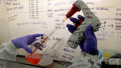 In this July 30 photo, Kai Hu, a research associate transfers medium to cells, in the laboratory at Imperial College in London. Imperial College is working on the development of a COVID-19 vaccine.