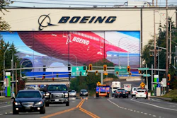 Traffic passes in view of a massive Boeing airplane production plant.