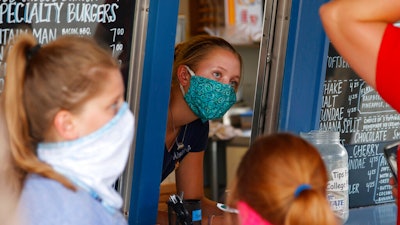 A staffer wears a mask while taking orders at a small restaurant in Grand Lake, Colo.