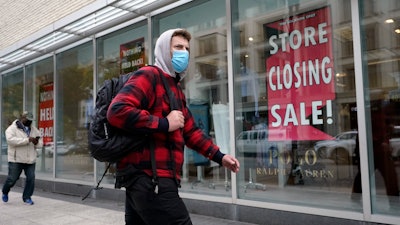 A passer-by walks past a store closing sign, right, in the window of a department store on Tuesday, Oct. 27 in Boston.
