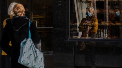 Two women wait in line at a bakery in Antwerp, Belgium, Nov. 4, 2020.