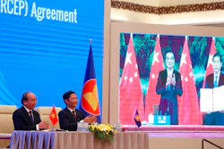 Vietnamese Prime Minister Nguyen Xuan Phuc, left, and Minister of Trade Tran Tuan Anh applaud next to a screen showing Chinese Premier Li Keqiang and Minister of Commerce Zhong Shan holding up the signed RCEP agreement, Hanoi, Nov. 15, 2020.