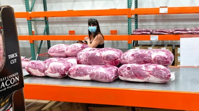 A shopper in a face mask looks over cuts of beef piled up in a cold room for purchase at a Costco warehouse store Tuesday, May 5, 2020, in west Denver. The U.S. economy rebounded at an even-stronger pace in the July-September quarter than first reported but a resurgence in the coronavirus is expected to slow growth sharply in the current quarter with some analysts even raising the specter of a double-dip recession.