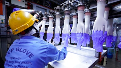 A worker inspects disposable gloves at the Top Glove factory in Shah Alam on the outskirts of Kuala Lumpur, Malaysia.