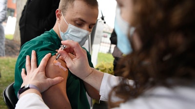 Colleen Teevan, System Pharmacy Clinical Manager at Hartford HealthCare, administers the Pfizer-BioNTech vaccine for COVID-19 to healthcare worker Connor Paleski outside of Hartford Hospital on Monday, Dec. 14 in Hartford, CT.