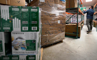 Ray Bellia stocks shelves with personal protective gloves, used by medical and law enforcement professionals, while unpacking pallets of other PPE goods in the warehouse of his Body Armor Outlet store on Dec. 9 in Salem, NH.