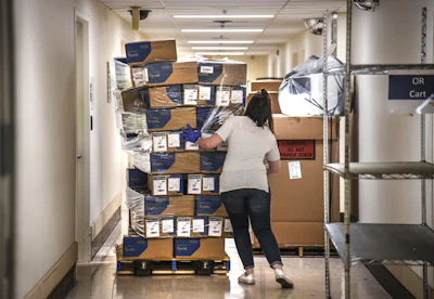 In this April 4 file photo, Bethany White, Providence Sacred Heart Medical Center supply chain manager, helps stabilize a shifting pallet of protective gowns as the third of five shipments of PPEs arrived at Sacred Heart from the state in Spokane, WA.